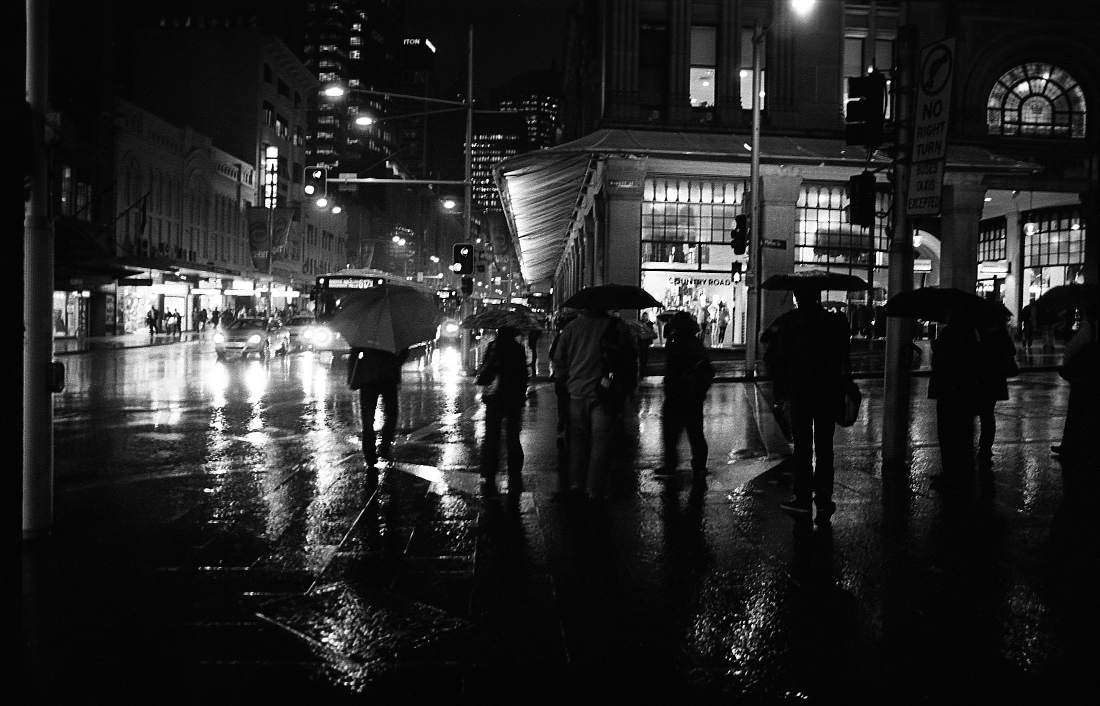 雨夜中撑伞的人们走过湿润的城市路口